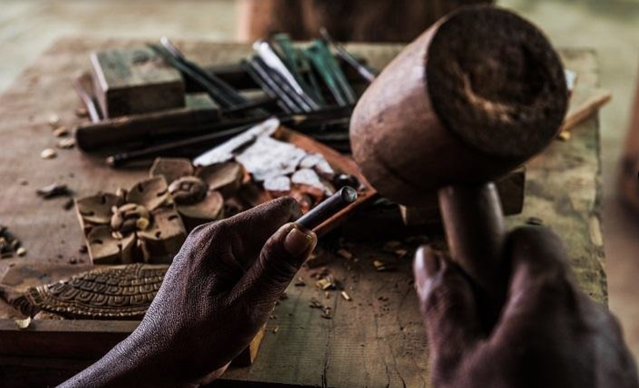 A skilled Nepalese artisan meticulously hand-carving a wooden frame using traditional techniques